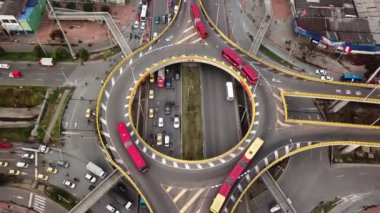 Bogota, Kolombiya, Latin Amerika 'daki Roundabout' ların insansız hava aracı görüntüleri. Bogota, Transmilenio 'da trafik vardı. En üst katta özel bir otobüs var. Kırmızı otobüslerle dolu ünlü bir döner kavşak. Yüksek kalite 4k görüntü.