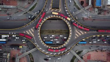 Bogota, Kolombiya, Latin Amerika 'daki Roundabout' ların insansız hava aracı görüntüleri. Bogota, Transmilenio 'da trafik vardı. En üst katta özel bir otobüs var. Kırmızı otobüslerle dolu ünlü bir döner kavşak. Yüksek kalite 4k görüntü.