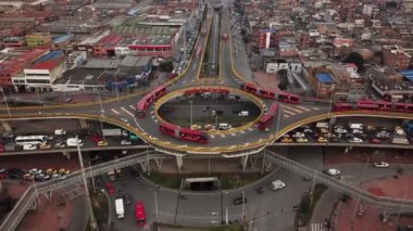 Bogota, Kolombiya, Latin Amerika 'daki Roundabout' ların insansız hava aracı görüntüleri. Bogota, Transmilenio 'da trafik vardı. En üst katta özel bir otobüs var. Kırmızı otobüslerle dolu ünlü bir döner kavşak. Yüksek kalite 4k görüntü.