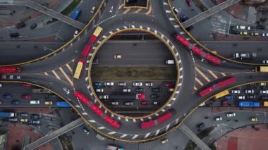 Bogota, Kolombiya, Latin Amerika 'daki Roundabout' ların insansız hava aracı görüntüleri. Bogota, Transmilenio 'da trafik vardı. En üst katta özel bir otobüs var. Kırmızı otobüslerle dolu ünlü bir döner kavşak. Yüksek kalite 4k görüntü.