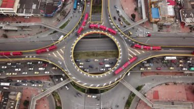 Bogota, Kolombiya, Latin Amerika 'daki Roundabout' ların insansız hava aracı görüntüleri. Bogota, Transmilenio 'da trafik vardı. En üst katta özel bir otobüs var. Kırmızı otobüslerle dolu ünlü bir döner kavşak. Yüksek kalite 4k görüntü.