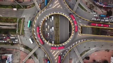 Bogota, Kolombiya, Latin Amerika 'daki Roundabout' ların insansız hava aracı görüntüleri. Bogota, Transmilenio 'da trafik vardı. En üst katta özel bir otobüs var. Kırmızı otobüslerle dolu ünlü bir döner kavşak. Yüksek kalite 4k görüntü.