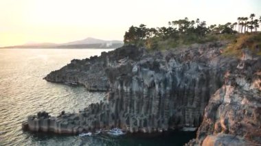 Jusangjeollidae veya Daepo Jusangjeolli Cliff Kore 'nin Jeju Adası' nda gün batımında. Volkanik kaya oluşumu, Güney Kore kıyılarındaki sütun bazalt kayalıkları. Yüksek kalite 4k görüntü.
