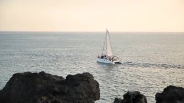 Jusangjeollidae ya da Daepo Jusangjeolli Kayalıkları yakınlarındaki Jeju Adası, Kore 'de günbatımında yelken açmak. Volkanik kaya oluşumu, Güney Kore kıyılarındaki sütun bazalt kayalıkları..