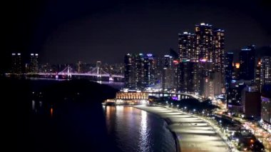 Güney Kore, Busan 'daki Haeundae Sahili' nin nefes kesici manzaralı lüks bir dairesinin en üst katından gece manzarası. Yüksek kalite 4k görüntü