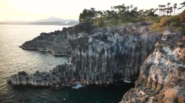 Jusangjeollidae veya Daepo Jusangjeolli Cliff Kore 'nin Jeju Adası' nda gün batımında. Volkanik kaya oluşumu, Güney Kore kıyılarındaki sütun bazalt kayalıkları. Yüksek kalite 4k görüntü.