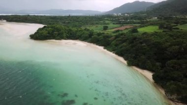 Japonya 'nın Okinawa bölgesindeki Ishigaki Adası' ndaki Kabira Körfezi 'nin insansız hava aracı görüntüleri. Turkuaz temiz su ve küçük yeşil adaları olan beyaz kumsal. Yüksek kalite 4k görüntü.