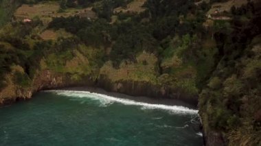 Portekiz, Madeira 'da gün batımında Seixal köyü etrafındaki nefes kesici bir dağ manzarası ve siyah plajın insansız hava aracı görüntüleri. Yüksek kalite 4k görüntü