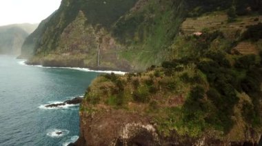 Portekiz, Madeira 'da gün batımında Seixal köyüne yakın bir şelale ve nefes kesici bir dağ manzarasının insansız hava aracı görüntüleri. Yüksek kalite 4k görüntü