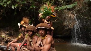 Tari, Papua Yeni Gine - 26 Mart, 25: Huli Wigmen Highland bölgesinin derinliklerinde küçük bir şelalenin yanında oturuyor. Kabile savaşçıları töreni. Papuan kabilesi dansı. Yüksek kalite 4k görüntü.