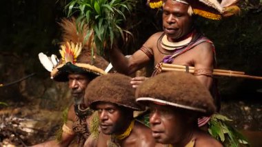 Tari, Papua Yeni Gine - 26 Mart, 25: Huli Wigmen Highland bölgesinin derinliklerinde küçük bir şelalenin yanında oturuyor. Kabile savaşçıları töreni. Papuan kabilesi dansı. Yüksek kalite 4k görüntü.