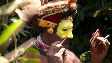 Tari, Papua Yeni Gine - 26 Nisan, 25: Huli Wigmen yüzlerini boyuyor. Highland bölgesindeki tören için hazırlık. Kabile savaşçıları töreni. Papuan kabilesi dansı. Yüksek kalite 4k görüntü.