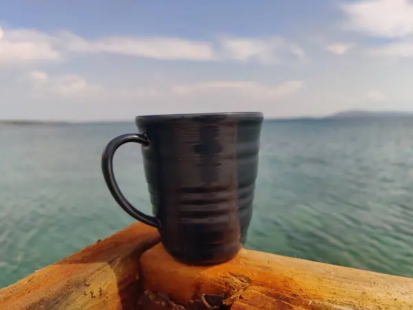 stock image Solitude in Serenity: A Dark Cup Embracing the Endless Horizon by the Seashore