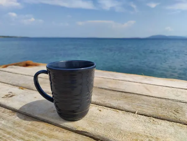 stock image Solitude in Serenity: A Dark Cup Embracing the Endless Horizon by the Seashore