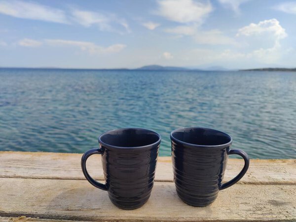 Общие моменты у моря: две чашки спокойствия против бесконечного синего, символизирующие связь и единство