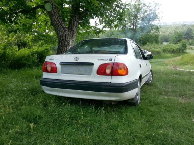 Türkiye, 21 Haziran 2014, Terk Edilmiş Toyota Corolla, bir ağacın altına park etti. Doğanın ıslah oluşunu sembolize ediyor..