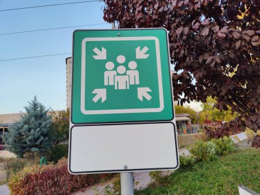 Emergency Gathering Point Sign: A Designated Safe Zone for People to Assemble in Case of Emergencies, Located in a Park Area with Green Surroundings and Clear Pathways clipart