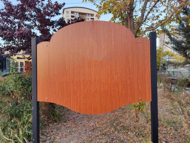 Bir Park Alanındaki Ahşap Bilgi Panosu: Ağaçlar ve Çalılarla çevrili bir Çevrede Görüntü Bildirimleri veya Bilgileri Göstermeye Hazır Boş İşaret