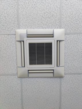 Temiz çizgiler ve minimalist bir tasarım gösteren benekli tavan paneline yerleştirilmiş kare havalandırma menfezi; desenli tavana zıt olan ızgara deseni, iç kısıma ince derinlik ekleyerek.