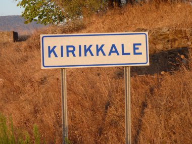 Mavi 'Kirklareli' Yazısı Metal Kutbunda: Kahverengi Çimen ve Yumuşak Gölgelerin Doğal Manzarasına Karşı Kalın Bir Zıtlık, Şehrin Kalbinde Serene Öğleden Sonra Yakalıyor.