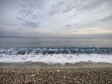 Sessiz Kıyı: Bitmeyen Ufuklar ve Geçici Dalgalar 'ın Metaforu, Çakıl Sessizliği' nin Dengesiz Güç ve Barış Dengesi 'ndeki Sessizliğin Ortasında Zamansız Sessizliği Yansıtarak Moody Gökyüzü' yle Buluştuğu Yer..