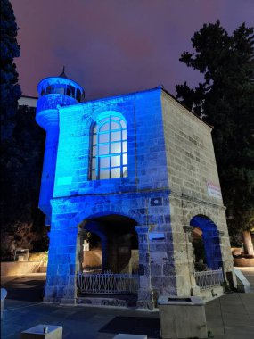 Antalya, Turkiye, December 16, 2024, The skele Mosque in Antalya Old Marina, Turkey, illuminated at night, highlighting its historical stone architecture and serene atmosphere under a purple sky. clipart