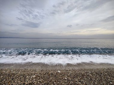 Sessiz Kıyı: Bitmeyen Ufuklar ve Geçici Dalgalar 'ın bir metaforu, Çakıl Sessizliği' nin Dengesiz Gökyüzü 'yle buluştuğu, Doğadaki Sessizliğin Ortasında Sessizliğin Ortasında Sessizliğin Yansıttığı,.