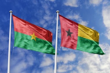 Bir Burkina Faso ve Gana bayrağı, Batı Afrika dayanışması için bir metafor, mavi gökyüzüne karşı birlikte el sallayarak dostluğu ve bölgesel birliği simgeliyor..