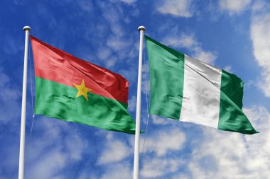 Burkina Faso ve Nijerya bayrakları, Afrika ulusları arasındaki birlik, dostluk ve kültürel değişimi sembolize eden canlı bir gökyüzü altında yan yana dalgalanıyor. Umut ve işbirliğinin bir metaforu meydan okumaların üzerinde yükseliyor, manzaraya karşı.