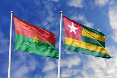 Bir Burkina Faso ve Togo bayrağı, Batı Afrika birliği için bir metafor, mavi gökyüzüne karşı birlikte el sallıyor, dostluğu ve bölgesel işbirliğini simgeliyor..