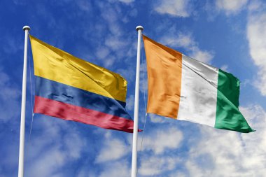 Kolombiya ve Fildişi Sahili bayrakları canlı mavi gökyüzüne karşı gururla dalgalanıyor. Uluslararası işbirliğini, diplomatik bağları ve küresel ilişkilerin canlı duvar halısını simgeliyor..