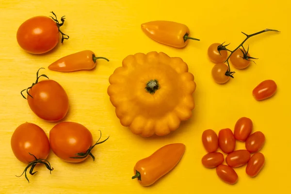 Yellow squash and peppers, tomato sprigs. Flat lay. Yellow background.
