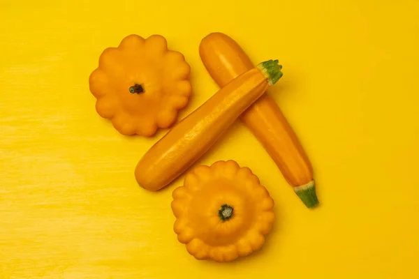 Two yellow squash and yellow two zucchini. Copy space. Flat lay. Yellow background.