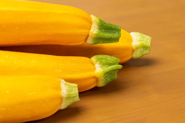 Yellow zucchini with green tails. Close up. Yellow background.
