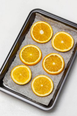 Fırın tepsisinde taze portakal dilimleri. Düz yatıyordu. Beyaz arkaplan.