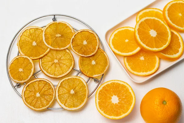 Fresh orange, fresh orange slices on plate. Dry orange slices on metal grill. Flat lay. White background.