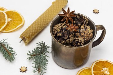 Metal bardakta koniler, bir mum, ladin dalları ve kuru portakal dilimleri. Noel süsleri. Üst Manzara. Beyaz arkaplan.