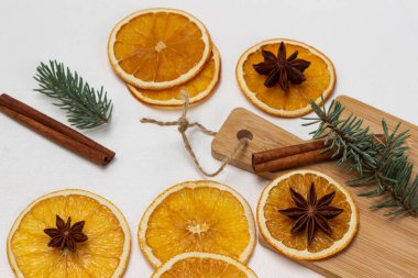 Kuru portakal dilimlerinde yıldız anason, tarçın ve ladin filizi güvertede ve masada. Beyaz arkaplan.