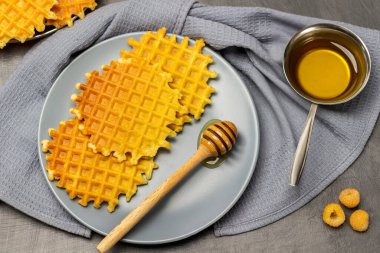 Yeşil tabakta bal balığı ve waffle. Metal kasedeki bal. Gri peçete. Düz yatıyordu. Gri arkaplan.