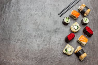 Farklı türde suşi. Uzayı kopyala Düz yatıyordu. Siyah yemek çubukları. Kahverengi arkaplan.