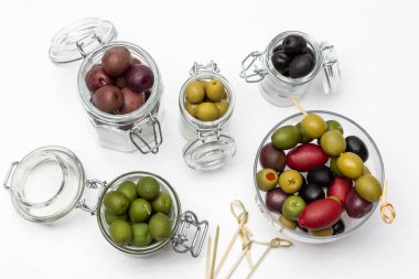 Olives in glass jars. Skewers on the table. Flat lay. White background.