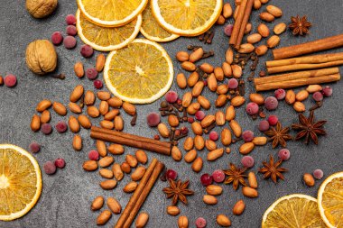 Frozen berries, spices, nuts and orange chips on a black background. Flat lay