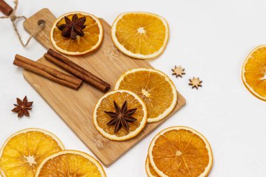 Dry orange slices, star anise and cinnamon sticks on a board. Top view. White background.