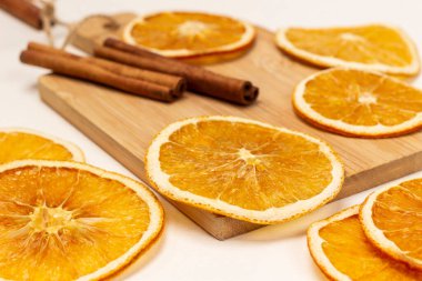 Dry orange slices on a board. Cinnamon sticks. Close up. White background.