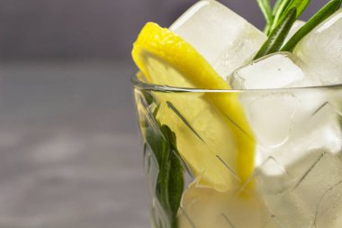 Lemon and pieces of ice in a glass. Part of the frame. Copy space. Close up. Gray background.