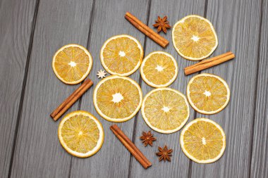 Yıldız anason, tarçın çubukları ve ahşap arka planda kuru portakal dilimleri. Düz yatıyordu