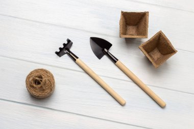 Beyaz arka planda turba tencereleri ve bahçe aletleri. Düz yatıyordu