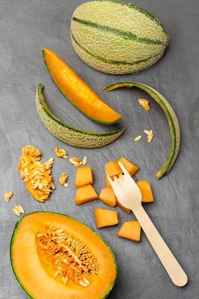 Een Halve Sinaasappelmeloen Meloenstukken Zaden Een Vork Meloenschil Grijze Achtergrond — Stockfoto