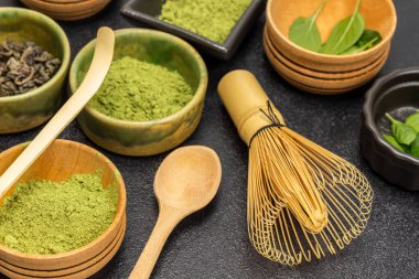 Bambu çırpma ve ölçme kaşığı. Kasede kibrit yeşil çay tozu. Kapatın. Siyah arkaplan