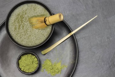 Kaşığı ve kibrit çay tozunu ölçmek, bambu çırpıcısını kibrit çayla karıştırmak. Düz yatıyordu. Uzayı kopyala Gri arkaplan.